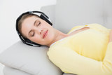 Woman listening music through headphones at home
