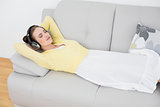 Woman listening music through headphones on sofa