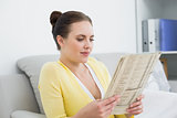 Woman reading newspaper on sofa