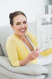 Smiling woman reading newspaper at home