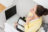 Woman with personal organizer and laptop at home