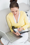 Woman using personal organizer and laptop at home