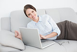 Portrait of a smiling well dressed woman using laptop on sofa