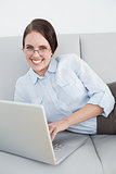 Smartly dressed smiling woman with laptop on sofa