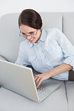 Smartly dressed woman using laptop on sofa