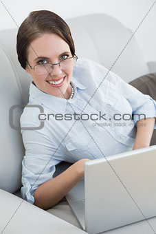 Portrait of a smartly dressed woman with laptop on sofa