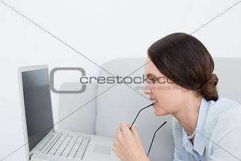 Side view of a woman using laptop on sofa