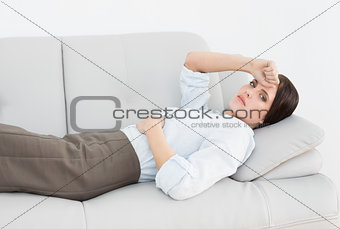 Portrait of a serious well dressed woman lying on sofa