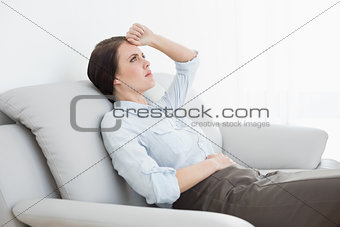 Serious well dressed woman sitting on sofa