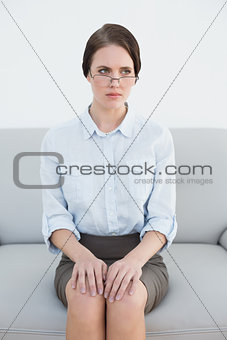 Displeased well dressed woman sitting on sofa