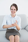 Smiling smart woman clapping hands on sofa