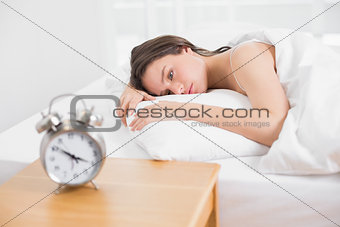 Woman in bed with alarm clock on bedside table