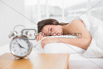 Woman in bed with alarm clock in foreground