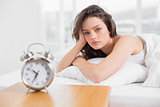 Beautiful woman in bed with alarm clock on bedside table