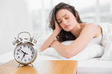 Sleepy woman with alarm clock in foreground