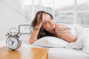 Beautiful young woman looking away while lying in bed