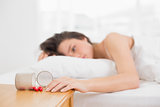Woman in bed by spilt bottle of pills on table