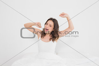 Portrait of a smiling woman stretching her arms in bed