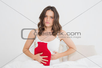Sad woman with a hot water bottle in bed