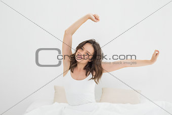 Smiling woman stretching her arms in bed
