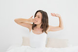 Woman yawning as she stretches in bed