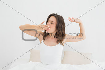Woman yawning as she stretches in bed