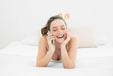 Cheerful casual woman using mobile phone in bed
