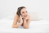 Smiling casual woman using mobile phone in bed