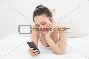 Casual woman looking at mobile phone in bed