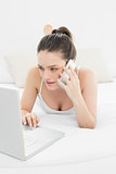 Serious casual woman using cellphone and laptop