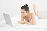 Relaxed casual woman using laptop in bed