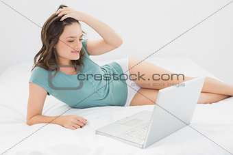 Casual young woman with laptop in bed