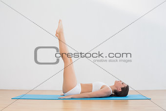 Sporty woman lying with raised legs on exercise mat