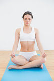 Toned woman sitting in lotus posture on exercise mat