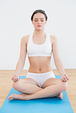 Toned woman sitting in lotus pose with eyes closed