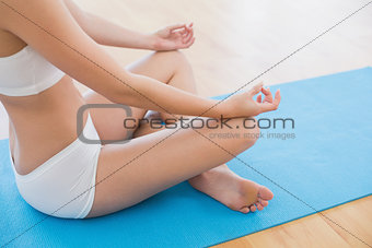 Side view of a slim cropped woman in lotus pose