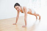 Beautiful sporty woman doing push ups in fitness studio