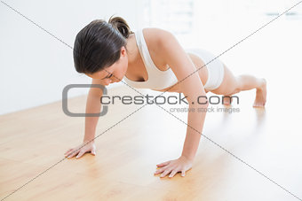 Sporty woman doing push ups in fitness studio