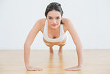 Sporty young woman doing push ups in fitness studio