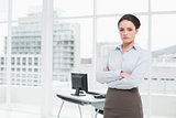 Elegant businesswoman standing with arms crossed in office