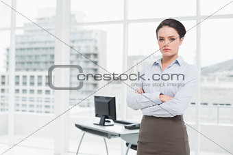 Elegant businesswoman standing with arms crossed in office