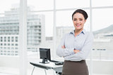 Elegant businesswoman smiling with arms crossed in office