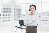 Smiling elegant businesswoman wearing headset with arms crossed in office