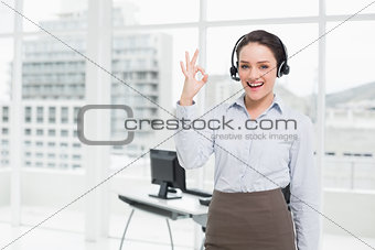 Businesswoman wearing headset while gesturing ok sign in the office