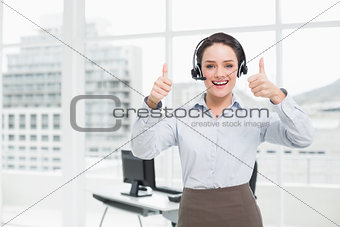 Elegant businesswoman wearing headset while gesturing thumbs up in office