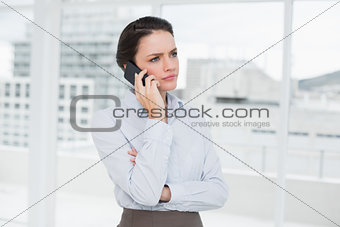 Serious elegant businesswoman using cellphone in office