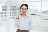 Elegant businesswoman gesturing thumbs up in office