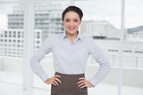 Elegant businesswoman standing with hands on hips in office