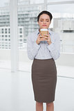 Elegant businesswoman enjoying coffee smell with eyes closed in office