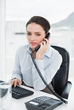 Businesswoman using landline phone at office desk